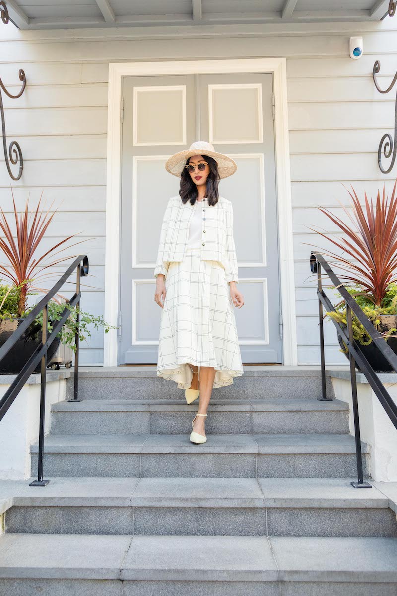 A brunette woman is walking down the stairs in a stunning matching plaid wool outfit