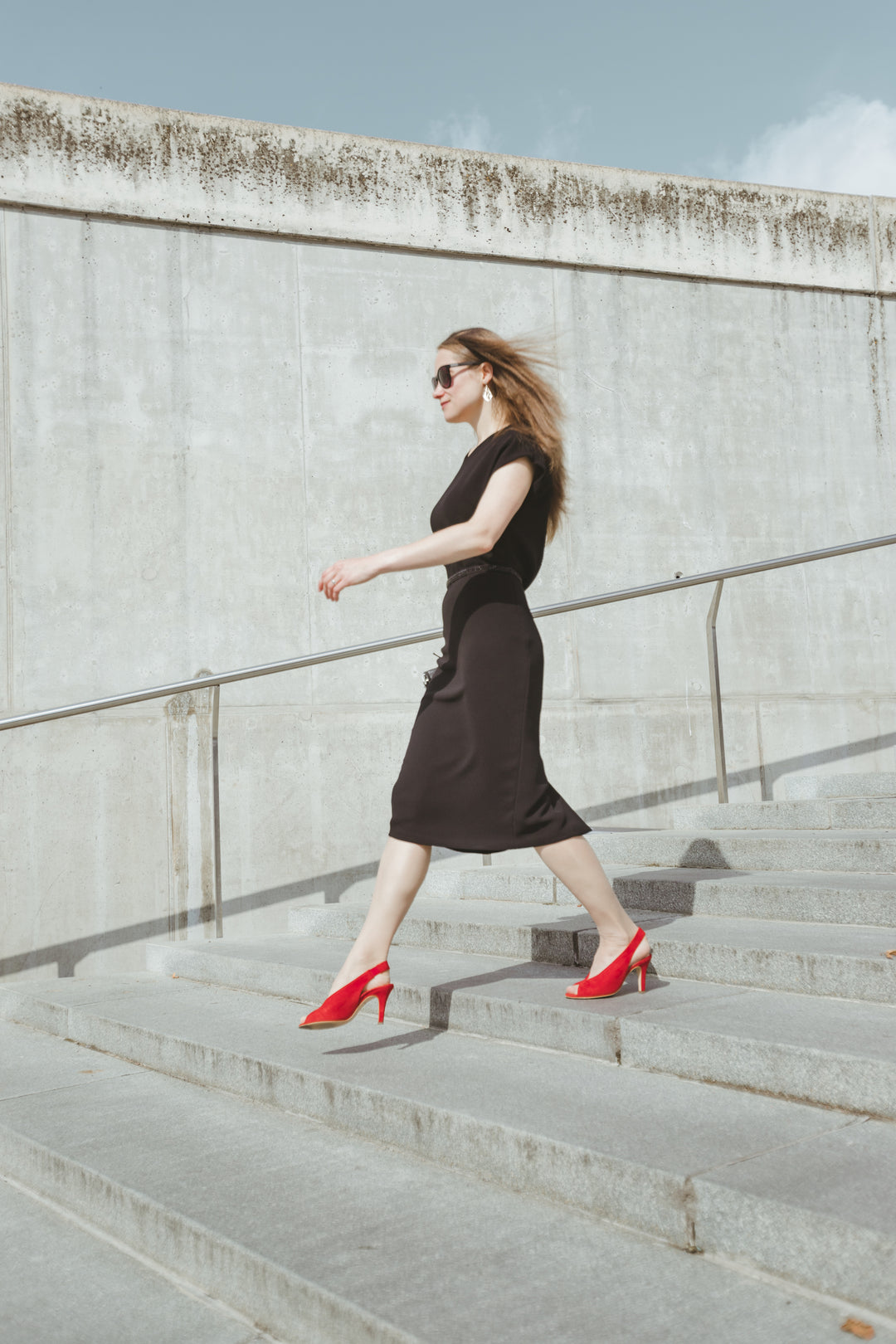 Designer is walking down the stairs in her iconic black pencil dress