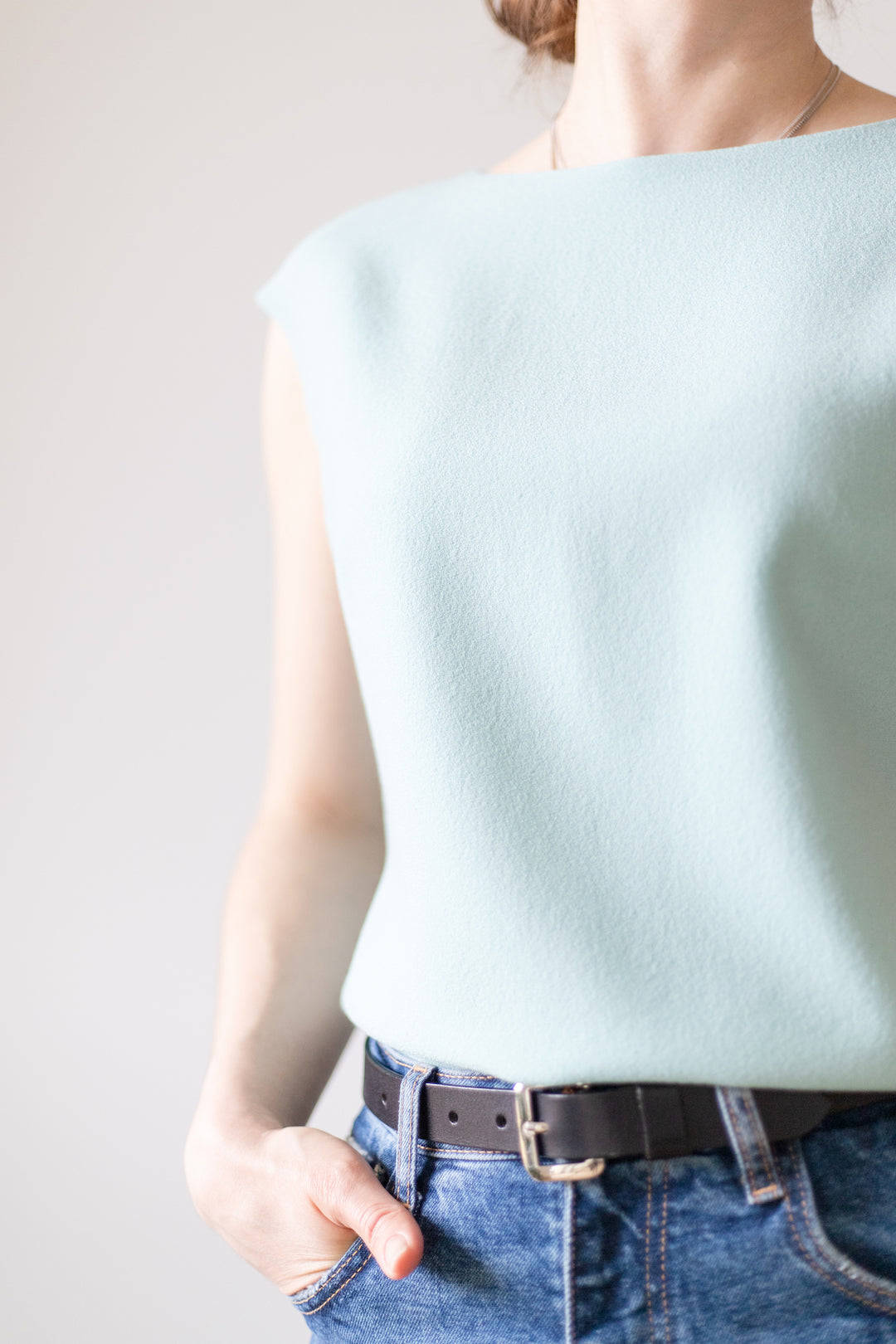 Woman is wearing an elegant mint green salvia wool crepe top