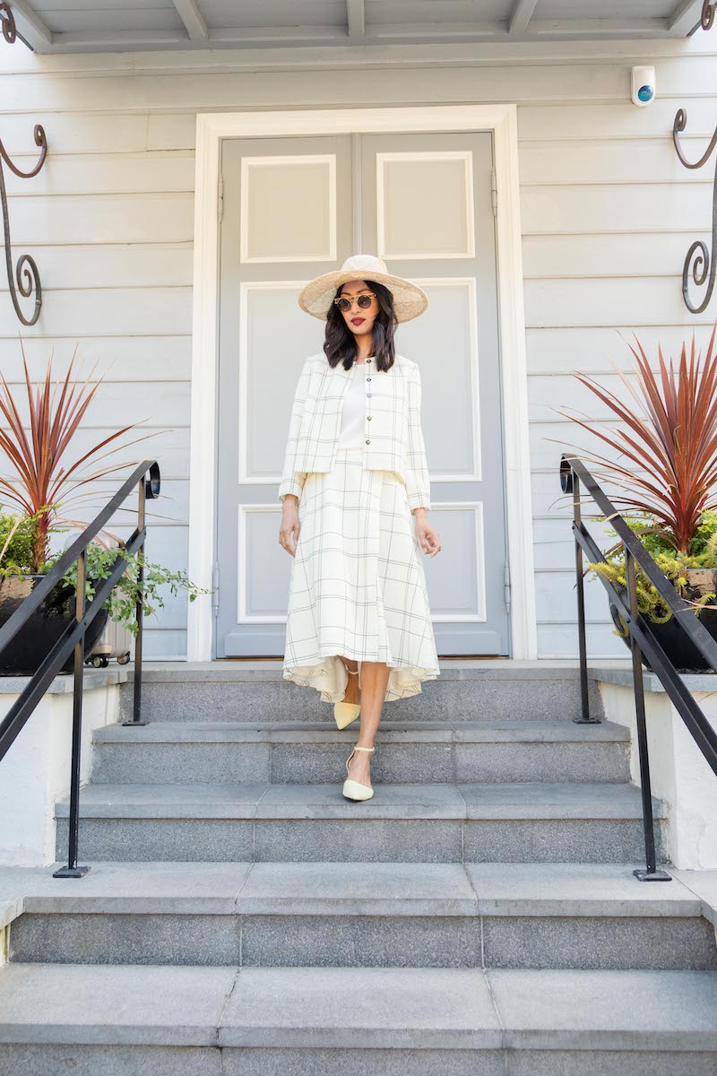 A brunette woman is walking down the stairs in a stunning matching plaid wool outfit 