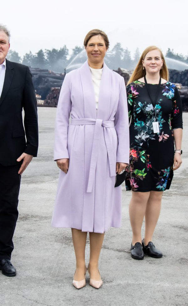 Three well-dressed people standing outdoors with a scenic background