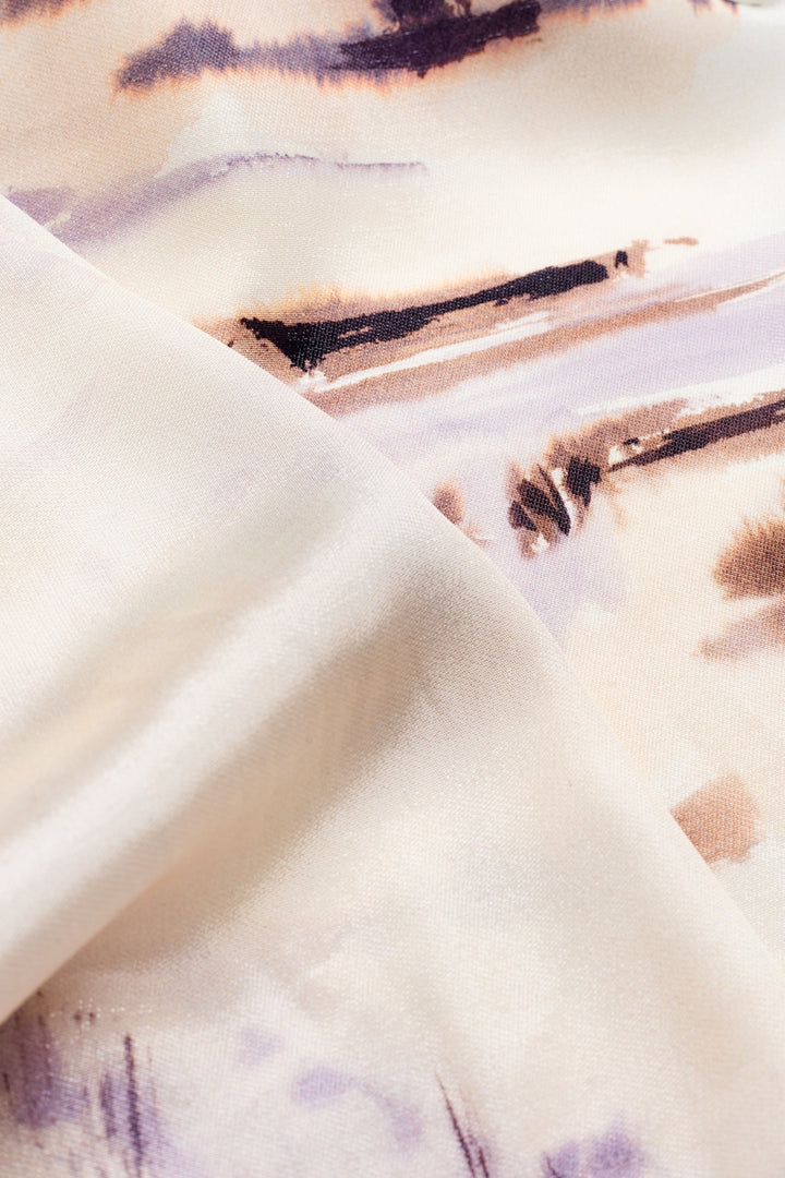 A close-up of draped fabric with an abstract watercolor-style print in cream, beige, light purple, and brown tones.