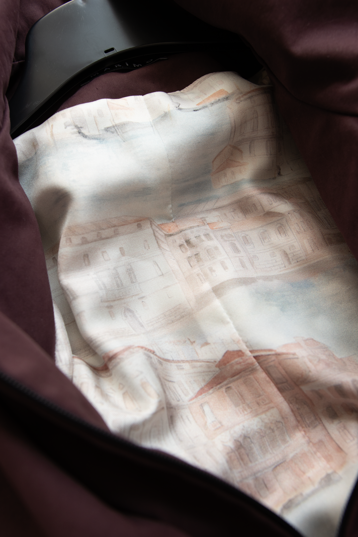 Silk lining detail of a luxury muted burgundy trench jacket.