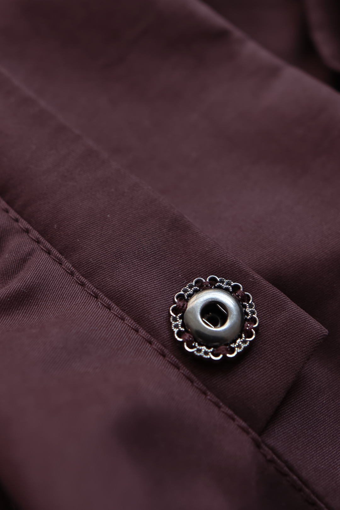 Detail of press button fastening on a minimalist luxury trench jacket.