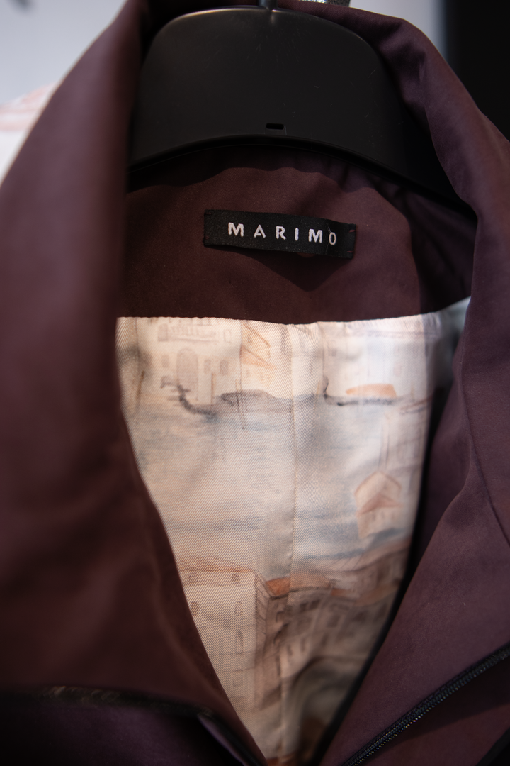 Lapel collar detail of a tailored burgundy trench jacket.