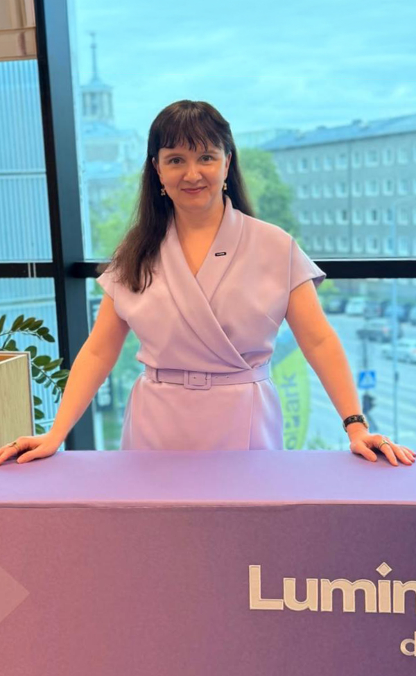 Woman in a light purple dress standing behind a counter