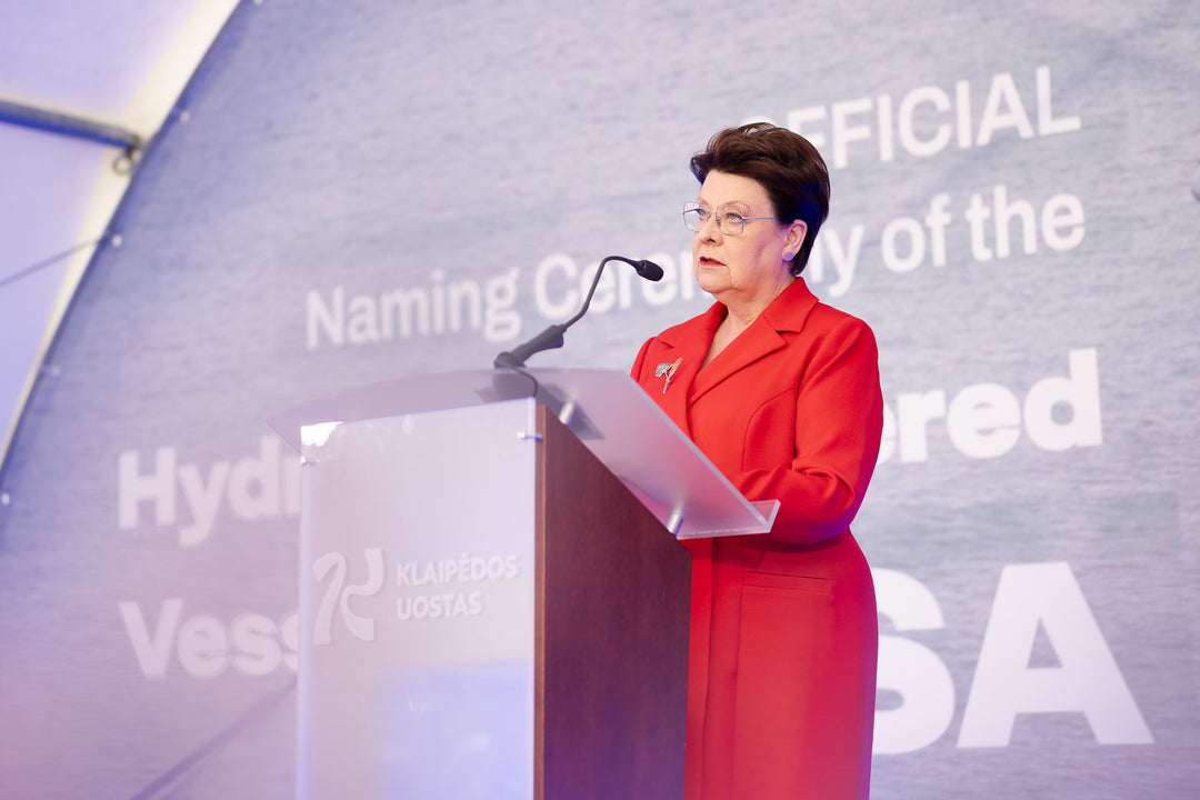 Woman in a red outfit standing at a podium with a branded backdrop
